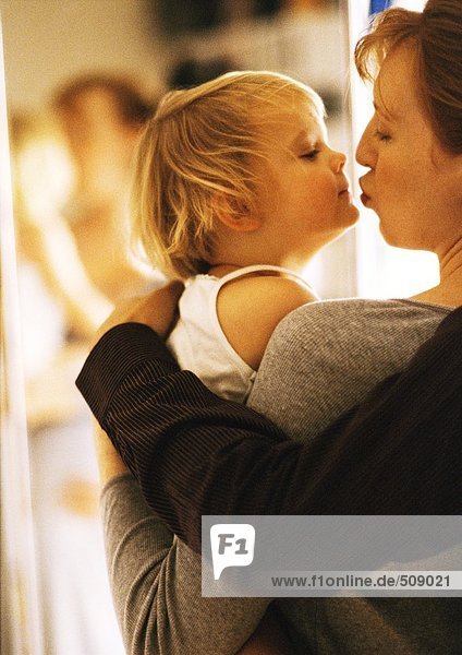 Frau hält und küsst Kind  Seitenansicht  Nahaufnahme
