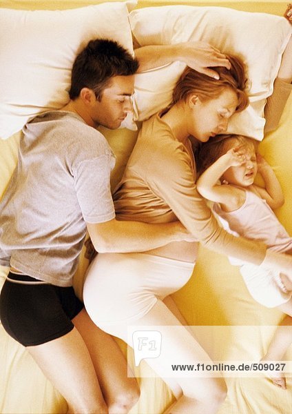 Mann  schwangere Frau und Kind im Bett liegend  erhöhte Aussicht