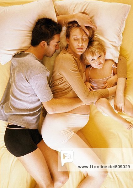 Man  pregnant woman and child lying in bed  elevated view