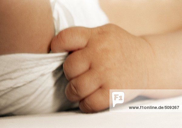 Baby's hand pulling on diaper  close-up