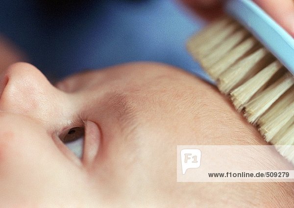 Baby mit gebürstetem Haar,  Nahaufnahme von Kopf und Bürste,  Teilansicht