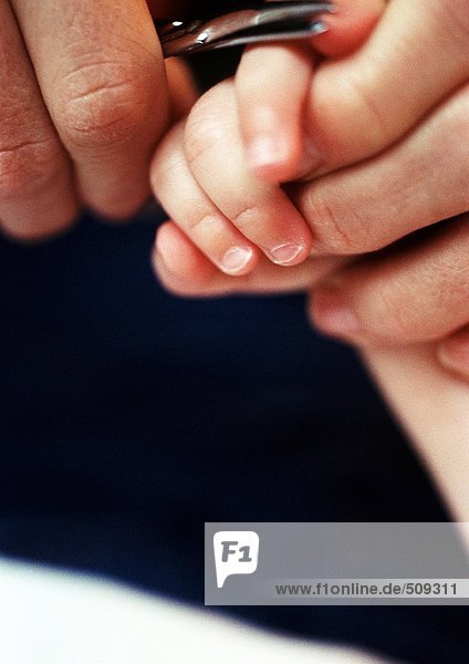 Erwachsene schneiden Babys Fingernägel  Nahaufnahme