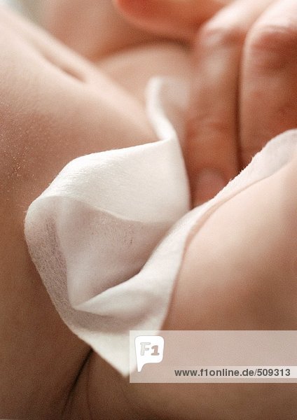 Adult hand wiping baby  close-up