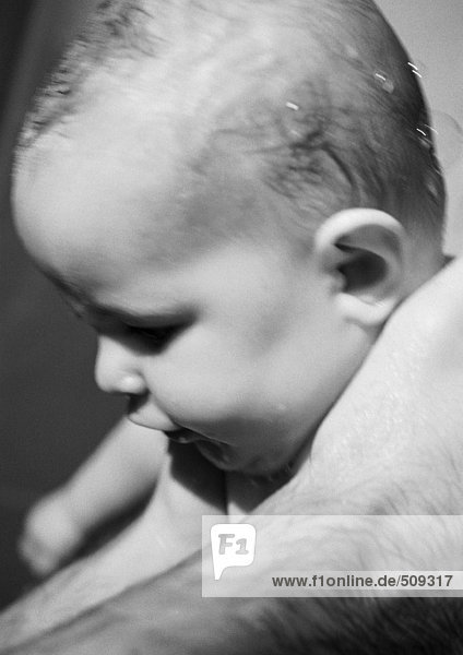 Baby mit nassen Haaren in den Händen des Vaters,  Nahaufnahme,  s/w