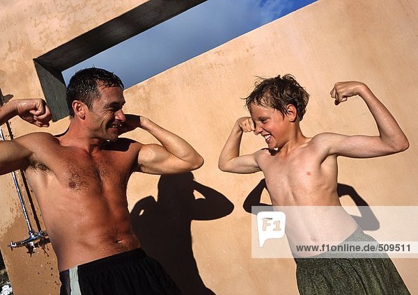Man and boy flexing arm muscles  making faces.