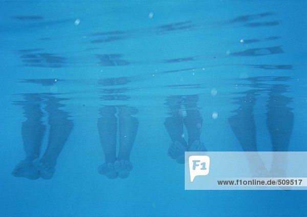 Vier Paar Füße und Waden  Unterwasseransicht