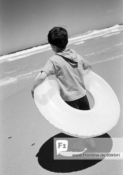 Kind im Schlauch am Strand stehend. SCHWARZWEIß