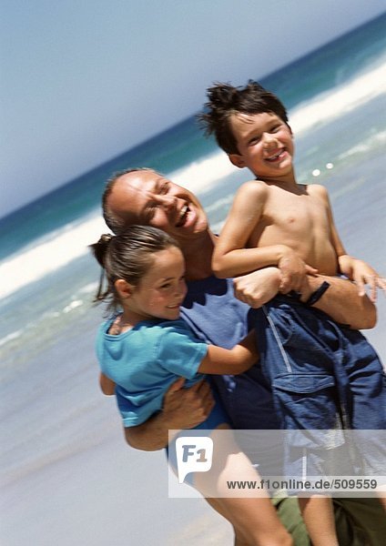 Mann mit zwei kleinen Kindern am Strand