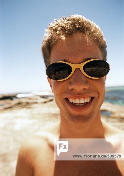 Close up of teenage boy wearing sunglasses at the beach.