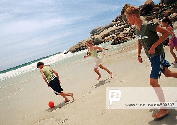 Junge Leute spielen Fußball am Strand