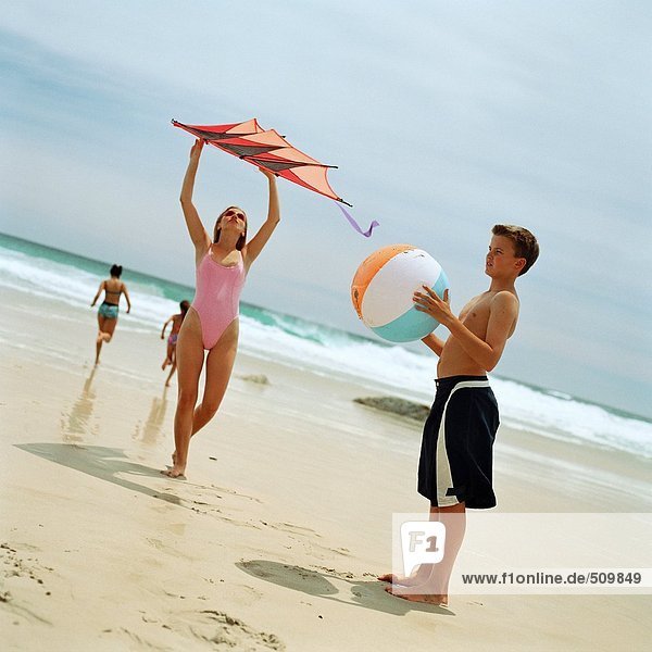 Teenager Junge mit Strandball  Mädchen mit Drachen am Strand