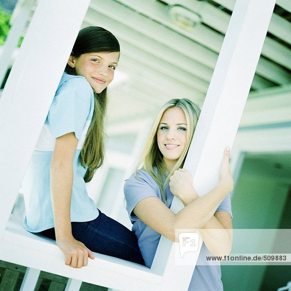 Junge Frau und Mädchen lehnen sich an die Pfosten auf der Veranda.