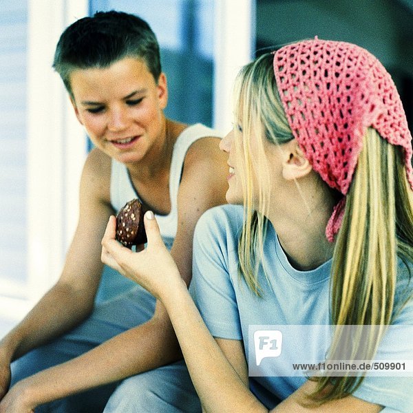 Junge Frau  die dem Teenager einen Brownie überreicht.