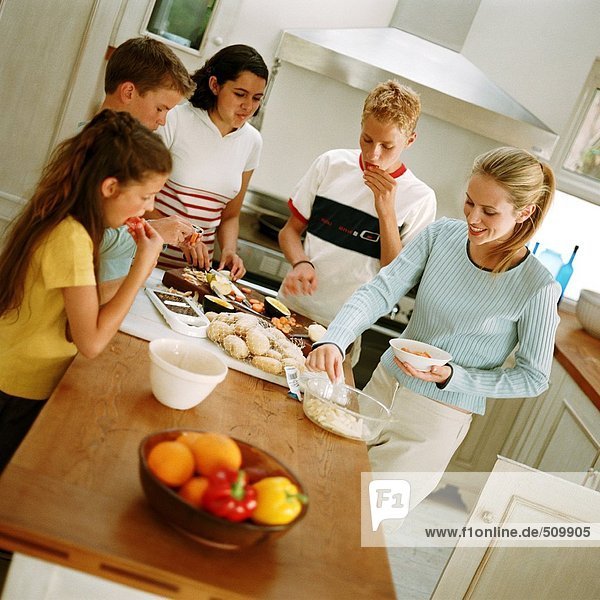 Young people snacking around table in kitchen