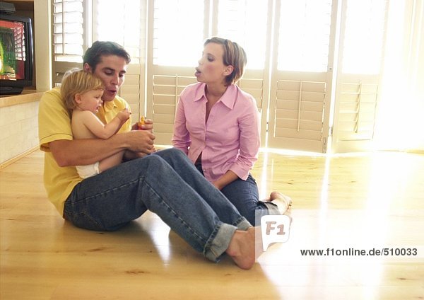 Couple sitting on floor  man holding baby