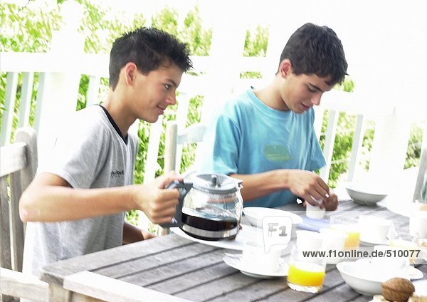 Zwei Teenager beim Frühstücken im Freien