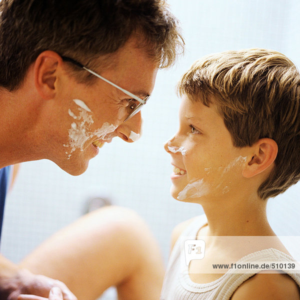 Vater und Sohn mit Rasiercreme im Gesicht  Seitenansicht