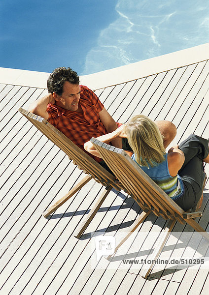 Man and woman sitting by swimming pool  high angle view