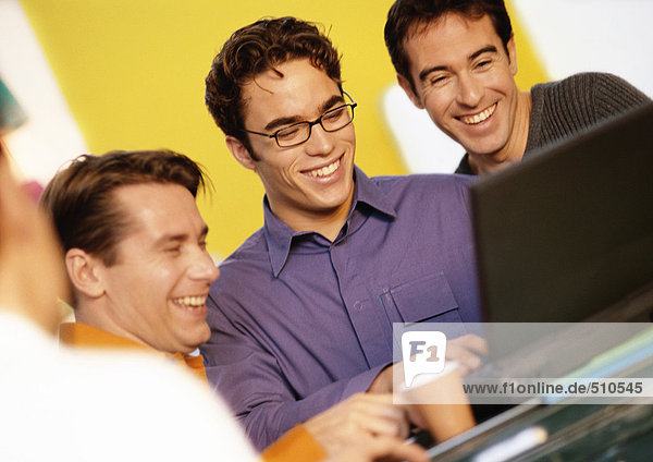 Drei Männer betrachten Laptop-Computer