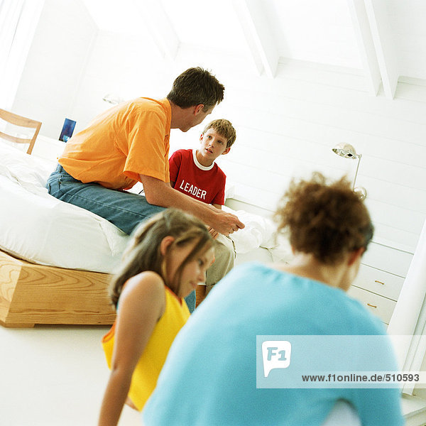 Eltern und Kinder sitzen im Schlafzimmer  Vater hat Herz zu Herz Gespräch mit Sohn