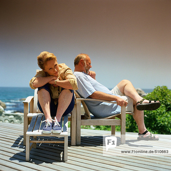 Mature couple sitting in deckchairs outside