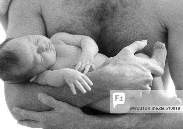 Oben-ohne Vater hält schlafendes Kind in den Armen vor der Brust  s/w