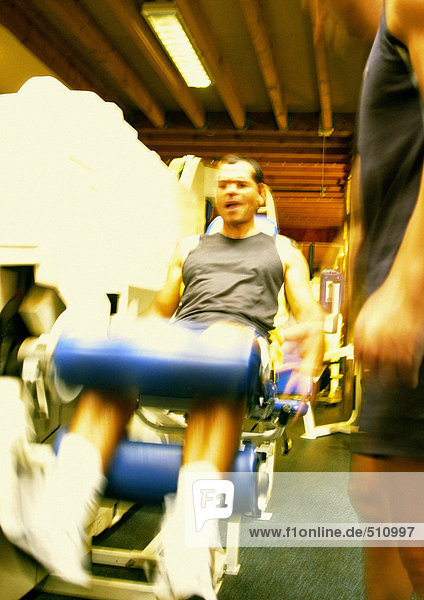 Mann mit Gewichtsmaschine im Fitnessstudio