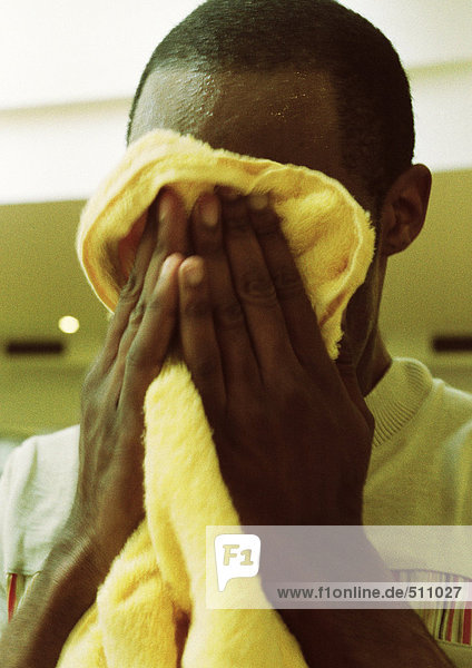 Mann wischt Gesicht mit Handtuch ab  Nahaufnahme