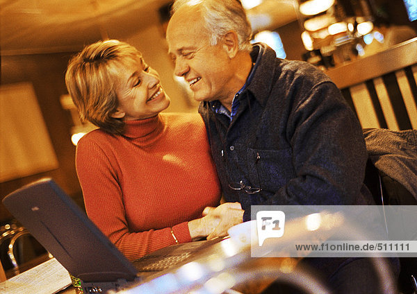 Mature couple sitting together with laptop.