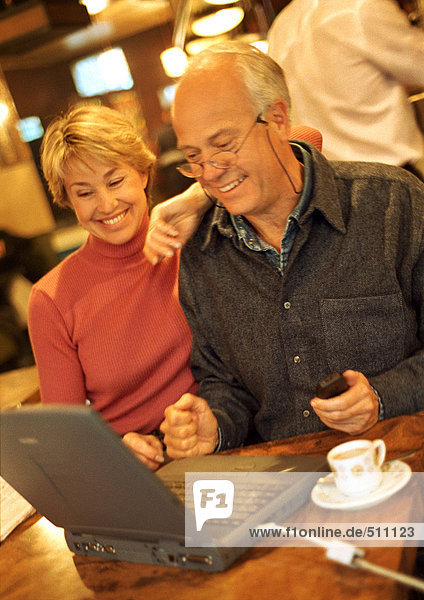 Mature couple in café using laptop.