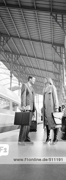 Geschäftsmann und Frau auf dem Bahnsteig stehend  volle Länge  s/w  vertikal