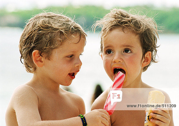 Two young children sharing popsicles  head and shoulders  portrait.