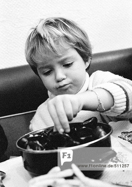 Kind isst Meeresfrüchte  Porträt  s/w.
