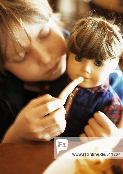 Kleines Mädchen füttert Puppe  Portrait.