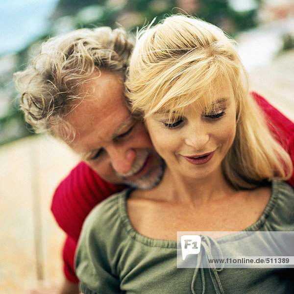 Man standing behind woman  chin resting on her shoulder