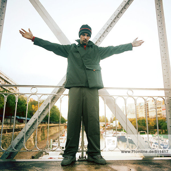 Man standing on bridge with arms stretched out