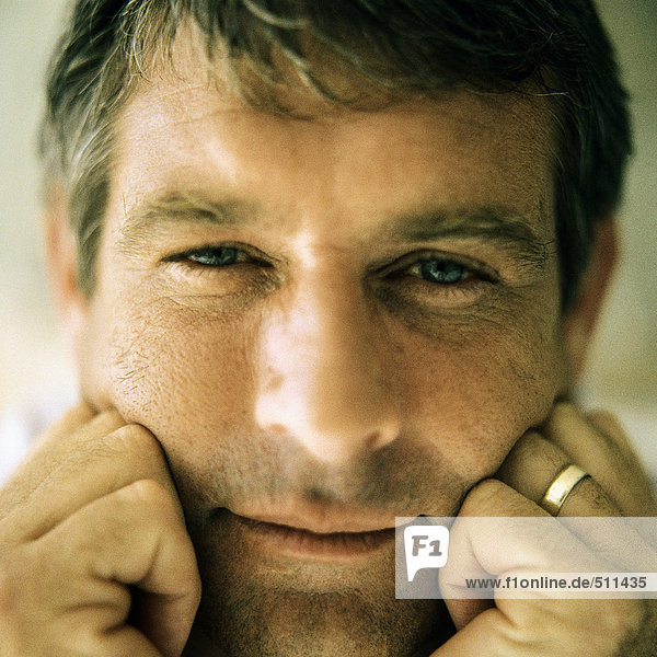 Portrait of man resting cheeks against both fists