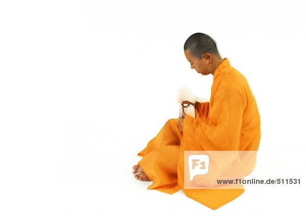 Buddhistischer Mönch sitzend  Seitenansicht