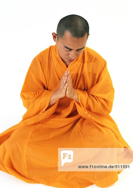 Buddhistischer Mönch sitzend  mit den Händen zusammen meditierend  hohe Blickwinkel