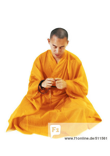 Buddhistischer Mönch sitzend und meditierend  Gebetsperlen haltend