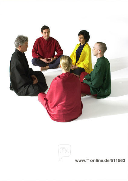 Gruppe von Menschen  die auf dem Boden sitzen und meditieren.
