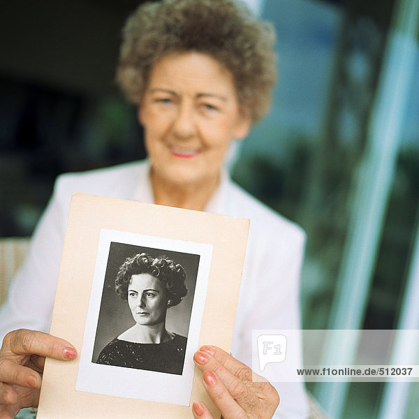 Seniorin zeigt Foto von sich selbst als jüngere Frau