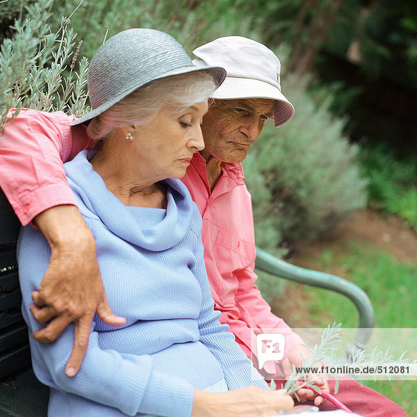 Seniorenpaar sitzend auf einer Bank im Freien