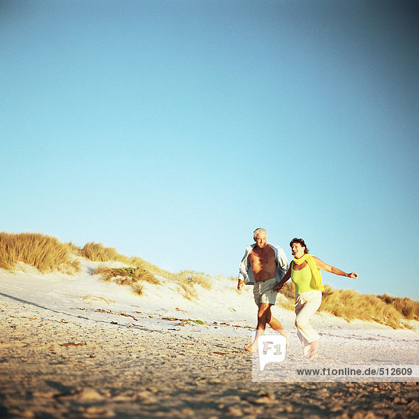 Mature couple running on beach