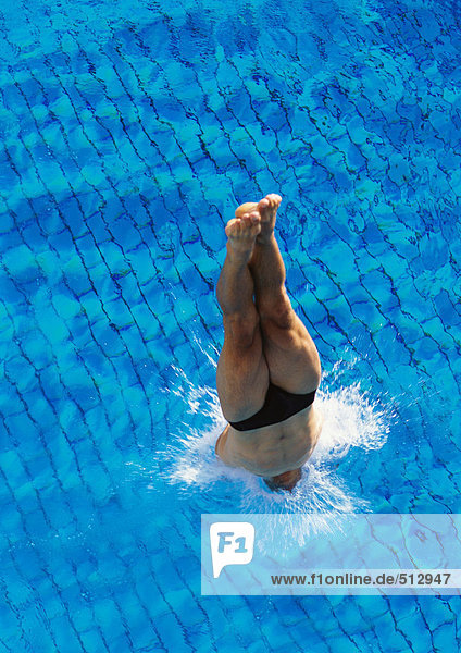 Männlicher Schwimmer taucht in das Schwimmbad ein  Blick nach oben