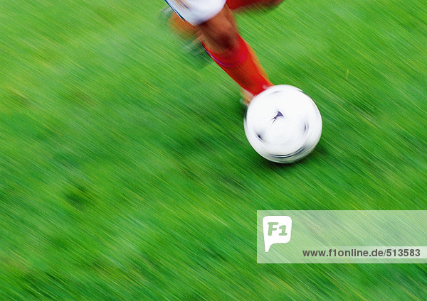 Fußballspielerbeine mit Ball  niedriger Schnitt  verschwommen  Gras im Hintergrund