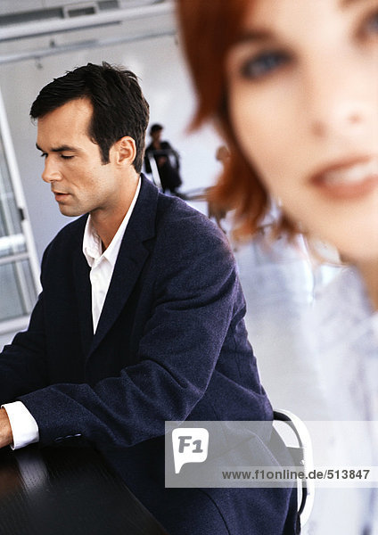 Businessman sitting at desk  woman smiling