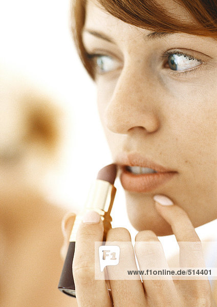 Woman using lipstick  close-up