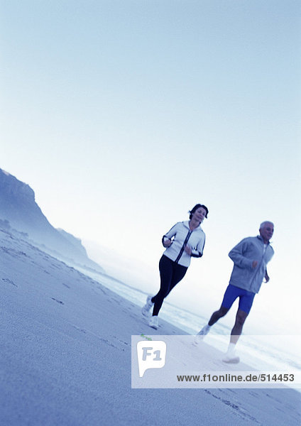 Mature man and woman running on beach
