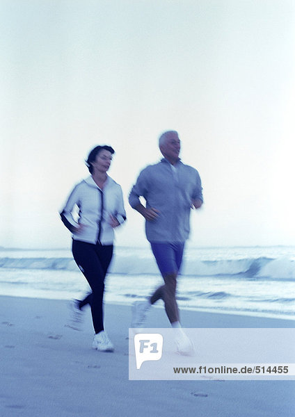 Mature man and woman running on beach